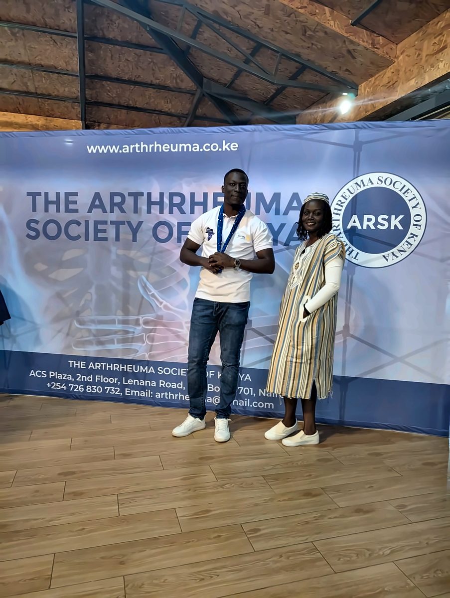 Two people in front of the Arthrheuma Society of Kenya backdrop