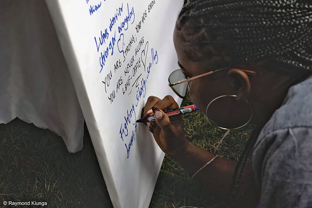 A community member writing a message on the World Lupus Day pledge wall