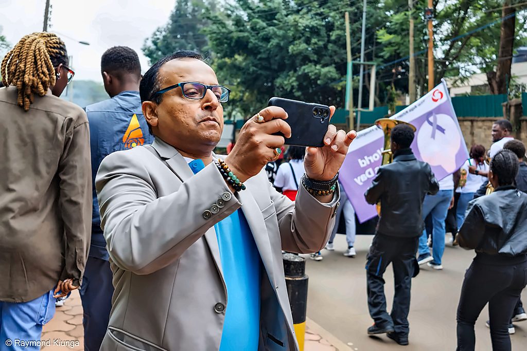 A supporter filming on a phone as the walk passes with the World Lupus Day banner
