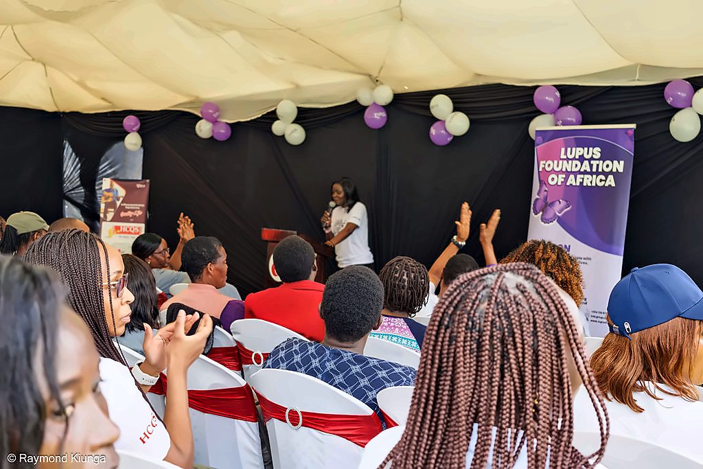 Hands raised in the audience during a session under the tent