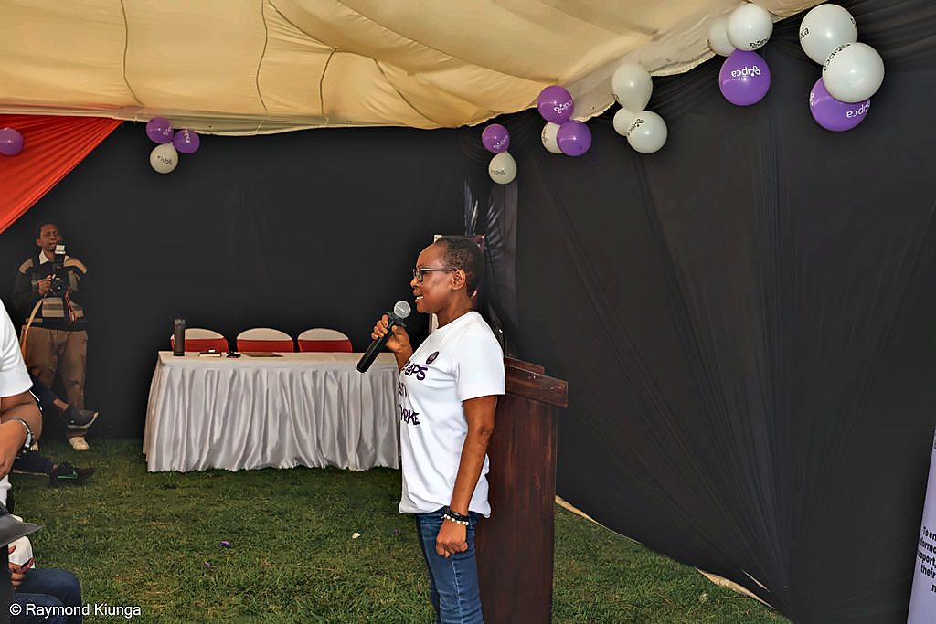 A speaker addressing the community from the stage under the tent