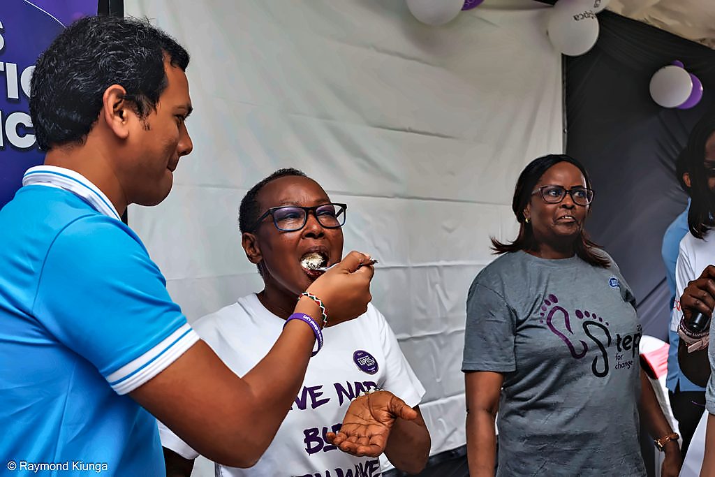 A guest offering a member a taste of the World Lupus Day cake