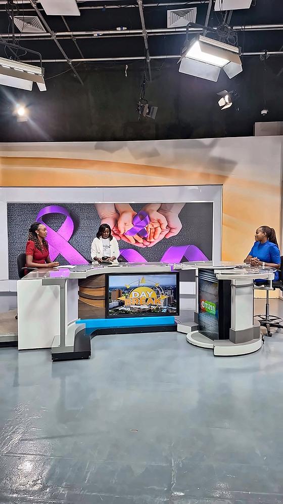 On the set of Citizen TV's Day Break, with a purple lupus ribbon on the screen behind