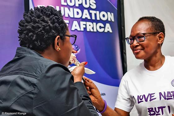 Two members sharing a bite of cake beside the LFA banner