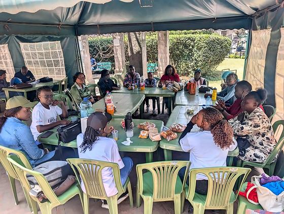 Members seated around tables under a tent at an LFA community meetup