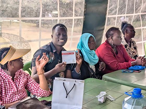 Members holding up cards and leaflets around a table at an LFA community meetup