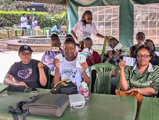 Members smiling and holding up cards at a table during an LFA community meetup